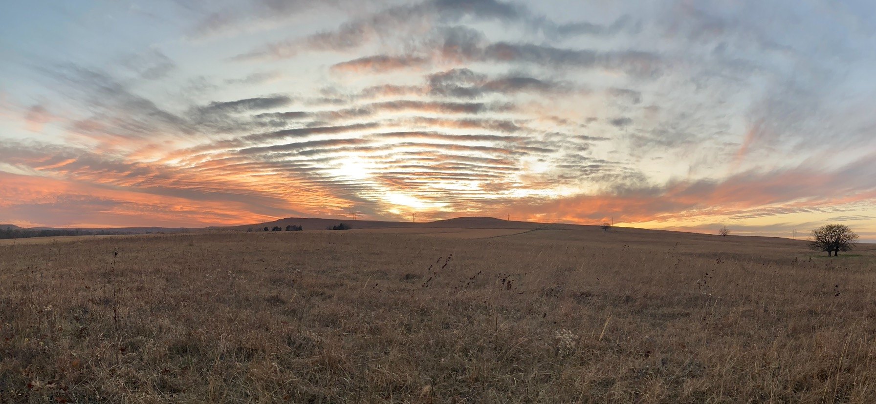 Panoramic Flint Hills prairie beneath a textured sunset sky